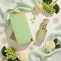 Lattafa Eclaire Pistache — Green box and bottle with gold accents, surrounded by pale green silk, white roses, and small