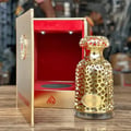 Lattafa Emeer By Lattafa Woody Scent 100ml — Gold ornate perfume bottle next to open red-lined display box on wooden table