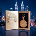 Lattafa Fakhar Extrait — Gold perfume bottle and ornate box displayed against a city skyline at night.