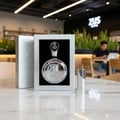 Lattafa Fakhar Platin — Silver perfume bottle and box displayed on a marble table with a blurred coffee shop background.