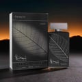 Lattafa Najdia Tribute by Lattafa 100ml EDP — Black perfume bottle and box with a prominent leaf vein design, set against a dramatic sunset sky background.