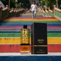 Lattafa Jasoor Eau de Parfum 100ml Unisex — Botol minyak wangi berhias emas dan kotak hitamnya dipamerkan di atas unjuran dengan tangga berwarna-warni di latar belakang.