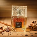 Lattafa Khamrah by Lattafa 100ml EDP Unisex — A square glass perfume bottle with amber liquid, featuring a textured glass cap and a black label with Arabic and English text. Surrounded by cinnamon sticks and star anise on a wooden surface.