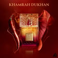Lattafa Khamrah Dukhan by Lattafa 100ml EDP Unisex — Botol minyak wangi mewah berpenutup geometri emas, berlatar belakang merah menyala dengan asap berpusar, cili merah, dan daun merah kering.