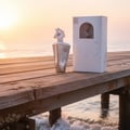 Lattafa Maahir Legacy by Lattafa 100ml EDP Man — Silver perfume bottle with horse head cap and white box on a wooden pier at sunset.