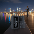 Lattafa Maahir Black Edition by Lattafa 100ml for Men — Black perfume bottle with horse head stopper in a gift box, with a city skyline and water reflections at night.
