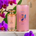 Lattafa Mayar by Lattafa EDP 100ml Woman — Pink perfume bottle and matching cylindrical box with gold accents, surrounded by purple orchids and green leaves on a marble surface.