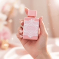 Lattafa Badee Al Oud Noble Blush — Hand holding a pink perfume bottle with a decorative white label and a pink cap, soft