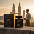 Rave Now Eau de Parfum — Black perfume bottle and box with geometric pattern, set against a city skyline with Petronas Twin Towers at sunset, man in traditional attire in background