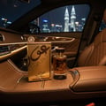 Lattafa Oudain by Lattafa Perfumes 100ml EDP for Men — Gold box and bottle of Oudain perfume displayed on a car's wooden console with a city skyline at night in the background.