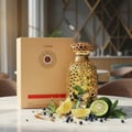 Lattafa Emeer By Lattafa Woody Scent 100ml — Gold ornate bottle with citrus slices, berries, and green leaves on a marble