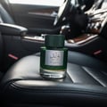 Lattafa Qaaed Intense by Lattafa 100ml EDP — Botol minyak wangi hijau bertekstur dengan label perak, diletakkan di atas tempat duduk kereta kulit hitam.