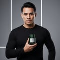 Lattafa Qaaed Intense by Lattafa 100ml EDP — Lelaki berbaju hitam lengan panjang pegang botol minyak wangi hijau bertekstur dengan label putih