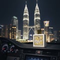 Lattafa Qaed Al Fursan Unlimited by Lattafa 90ml EDP — White perfume bottle with gold cap and intricate yellow design, placed on a car dashboard at night with the Petronas Twin Towers in the background.