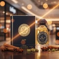 Lattafa Raed Luxe by Lattafa 100ml EDP Unisex — Botol minyak wangi tona emas dan kotak birunya dipamerkan di atas permukaan kayu, dengan batang kayu manis, bunga lawang, dan buah pelaga di sekelilingnya. Lampu bokeh lembut kelihatan di latar belakang.