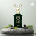 Lattafa Safeer by Lattafa Al Noble 100ml EDP — Green velvet bottle with gold deer head cap, displayed on wet rocks with pine sprigs and cones.