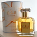 Lattafa Sutoor 100ml EDP for Women — A clear glass perfume bottle with gold accents and a crystal-embellished cap, next to its matching white and gold patterned cylindrical box.
