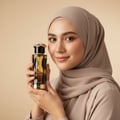Lattafa Teriaq Intense by Lattafa 100ml Eau de Parfum — Woman in a beige hijab holding a perfume bottle with a snake-shaped gold cap against a plain beige background.