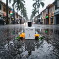 Maison Alhambra Alpine Homme Sport By Maison Alhambra Men 100ml — White perfume bottle with black cap, surrounded by orange slices, pine cone, and leaves, reflected on wet asphalt street with palm trees and buildings in the background.