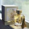 Maison Alhambra Anarch by Maison Alhambra 100ml EDP Women — A clear glass perfume bottle with a gold cap and a gold tassel, featuring a gold Celtic knot design and the "ANARCH" logo. A matching white and gold box is visible behind it.