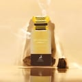 Maison Alhambra Mysterious Amber 80ml — A clear glass perfume bottle with a gold cap, featuring the text 'MYSTERIOUS AMBER EAU DE PARFUM' and the Maison Alhambra logo, surrounded by wood pieces and smoke effects against a golden background.