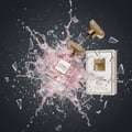 Maison Alhambra Como Moiselle by Maison Alhambra 100ml untuk Wanita — Botol minyak wangi meletup dengan percikan cecair merah jambu, serpihan kaca pecah, dan penutup emas terpisah, dengan kotak putih di latar belakang.