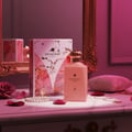Maison Alhambra Decadent Dream — Pink perfume bottle and box with marble and gold accents, rose petals, pearl bracelet, and gold necklace on a marble surface.