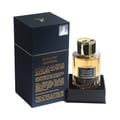 Maison Alhambra Exclusif Saffron — Amber glass perfume bottle with gold cap, presented in a dark blue box with gold lettering, isolated on white.
