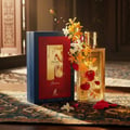 Maison Alhambra Renee Carmine EDP 100 ml Maison Alhambra — Perfume bottle and box adorned with vibrant orange and red flowers, petals scattered on a patterned cloth.