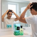 Maison Alhambra Jean Lowe Vibe by Maison Alhambra 100ml EDP — Man styling hair in bathroom mirror, with perfume bottle and box on counter.