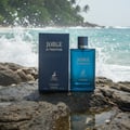 Maison Alhambra Jorge Di Profondo Deep Blue by Maison Alhambra 100ml Men — Blue glass perfume bottle and navy box on wet rocks with ocean waves crashing in the background.