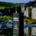 Maison Alhambra Jorge Di Profumo — Black matte perfume bottle with silver accents, featuring 'Jorge Di Profumo' and a deer logo, set against a blurred background of stone ruins and greenery.