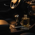 Maison Alhambra Kismet For Men — Gold-capped glass perfume bottle with golden liquid, placed on a car's center console next to the gear stick.