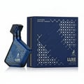 Maison Alhambra Luxe Journey — Blue glass perfume bottle with intricate white geometric pattern and gold deer logo, next to a matching navy blue gift box with white geometric design and gold deer logo.