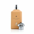 Maison Alhambra Decadent Wonder Her EDP 100 ml — A tall, matte peach-colored perfume bottle with a silver spray nozzle stands upright, next to its ornate silver cap with a black gem accent. The bottle features 'DECADENT WONDER' text and a deer logo.