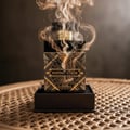Maison Alhambra Infini Elixir Maison Alhambra 100ml EDP Men — Black and gold patterned perfume bottle with smoke rising from the cap, presented in a dark box on a woven surface.