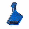 Maison Alhambra Luxe Journey — Blue glass perfume bottle with intricate gold pattern and geometric cap, angled view.