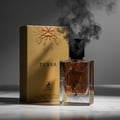 Maison Alhambra Terra — A clear glass perfume bottle with brown liquid and a cracked glass effect, standing next to its gold box with a tree root design. Dark smoke billows from the bottle.