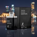 Maison Alhambra Man Black Edition — Black perfume bottle and box set against a blurred city night background with bokeh lights.