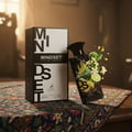Maison Alhambra Mindset by Maison Alhambra – 100 ml For Man, with a perfume bottle and its box on a patterned cloth, surrounded by lime slices and white flowers.