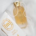 Maison Alhambra Musk Vanille by Maison Alhambra 100ml EDP — Frosted glass perfume bottle with gold cap, a pearl necklace draped around it, and a matching white and gold presentation box.