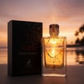 Maison Alhambra Toro Pour Homme — Black box and clear glass perfume bottle with golden liquid, set against a beach sunset with palm trees and sparkling light effects.