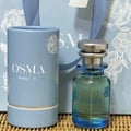 Osma Osma Ambry A Fresh & Fly 75ml EDP — A light blue cylindrical box with white floral patterns and the Osma logo sits next to a clear glass perfume bottle with blue accents and a silver cap, against a light blue background with floral patterns.