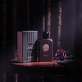 Paris Corner Black Optra by Paris Corner Pendora Scents — Black glitter perfume bottle and box with a purple rose and black lace on a wooden table, dark floral background