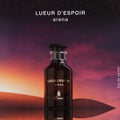 Paris Corner Lueur D Espoir Ambre by Emir Paris Corner 100ml — A dark glass perfume bottle with gold lettering sits on a reflective surface against a desert dune background at sunset with a starry sky above.