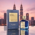 Paris Corner Satin Luxe oleh Paris Corner Pendora Scents 100 ml — Botol minyak wangi kaca biru bertudung emas dan kotak biru sepadan, berlatar belakang langit bandar waktu senja.