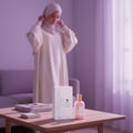 Volare Amaranth Niche by Volare – 100 ml for Her. A woman in a cream hijab adjusts her headscarf behind a wooden table displaying the perfume box and bottle.