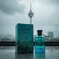 Volare Amazon Rainfall by Volare 100ml EDP Men — A teal box and a teal glass perfume bottle sit on a wet surface with raindrops on a window in the background, showing a distant tower.
