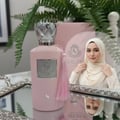 Volare Darlene Pour Femme – Pink perfume bottle with silver cap and pink tassel, next to a pink box and a woman in a cream hijab, on a mirrored tray with greenery.