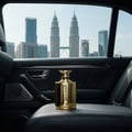 Volare Reload Gold by Volare Man – 100 ml untuk Lelaki, botol minyak wangi emas tertulis 'RELOAD', diletakkan di atas tempat duduk kereta dengan pemandangan bandar KL Menara Berkembar Petronas di latar belakang.